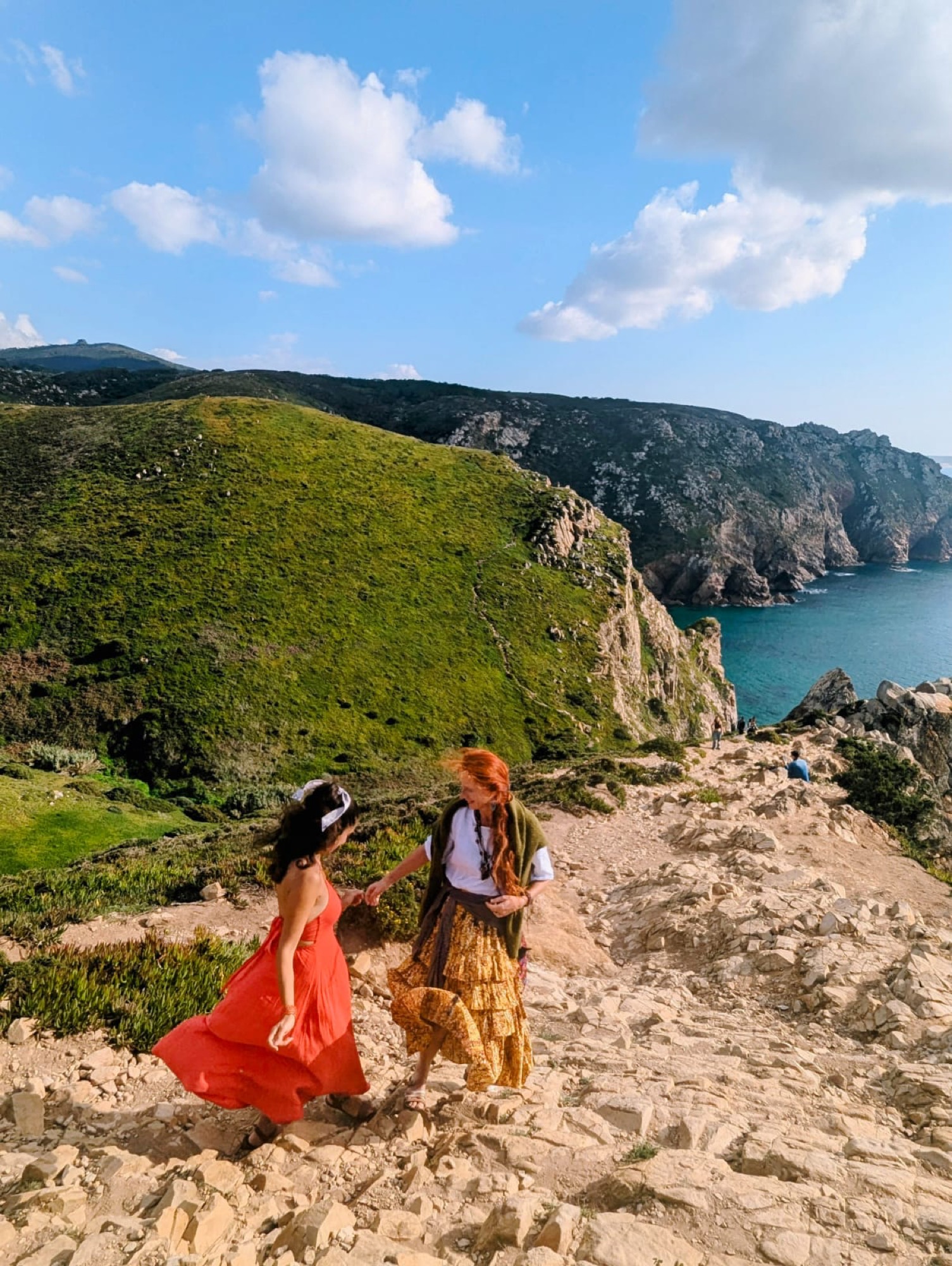 Agata Algierska and Tula Mirjan walking hand in hand along the Portuguese coastline